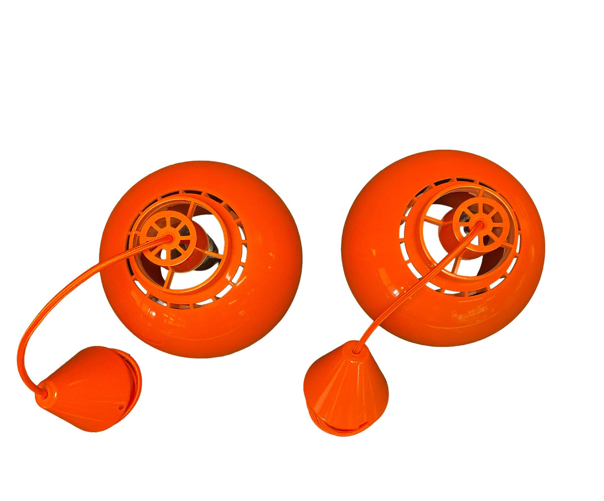Two orange plastic reels with attached strings on a white background