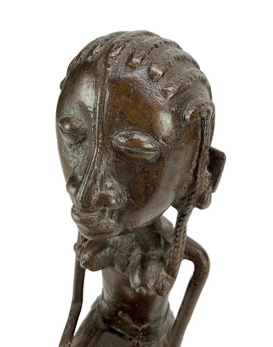 Bronze sculpture of a man's head with braided hair on a white background