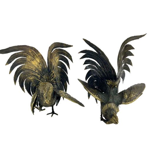 Two metallic rooster sculptures on a white background
