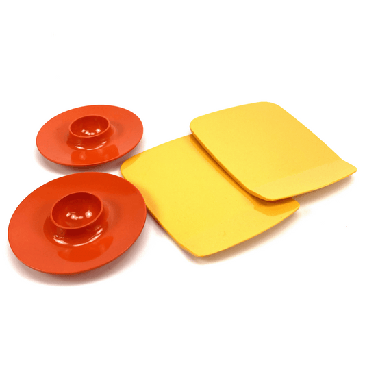 Two orange plates and two yellow coasters on a white background