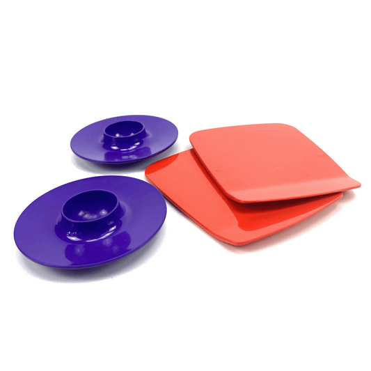 Set of colorful Rosti including purple egg cups and red buttering boards, on a white background