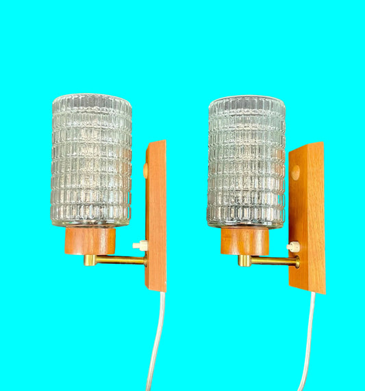 Pair of wall sconces with glass shades and wooden frames on a turquoise background