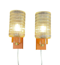 Load image into Gallery viewer, Two wall-mounted lamps with textured glass shades and wooden bases on a white background.

