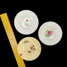 Load image into Gallery viewer, Three decorative ceramic plates with floral designs on a black background, with a ruler for scale.
