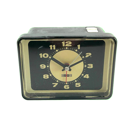 Vintage-style alarm clock with black and gold design, bright-green background