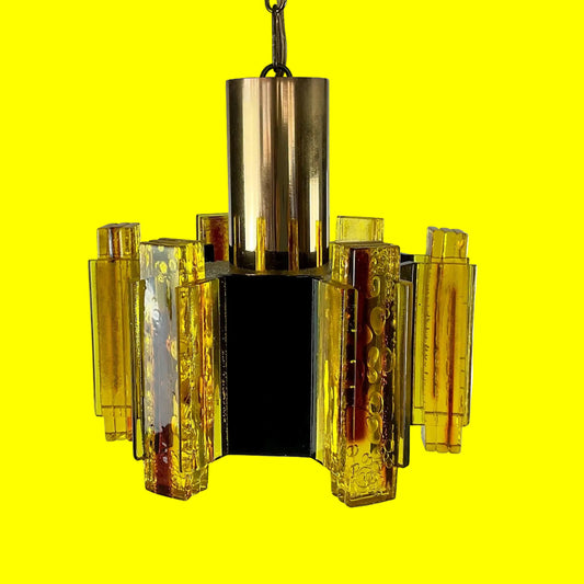 Yellow glass chandelier with brass accents on a yellow background