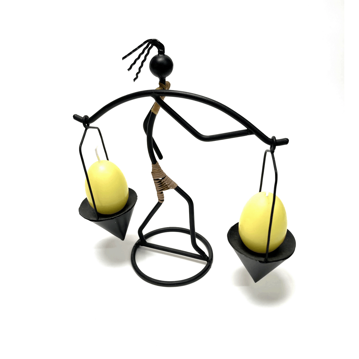 Decorative candle holder shaped like a person balancing two candles on a white background