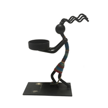 Load image into Gallery viewer, Metallic sculpture of a figure with a colorful striped garment holding a bowl on a white background
