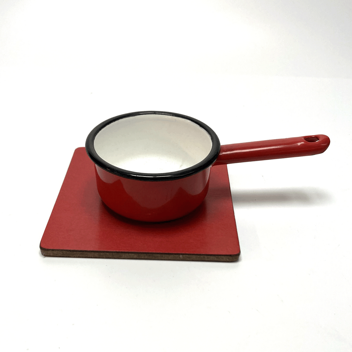 Red enameled cast iron saucepan on a matching red trivet against a white background
