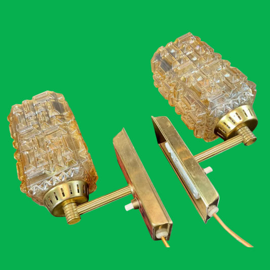 Pair of gold wall sconces with textured glass shades on a white background